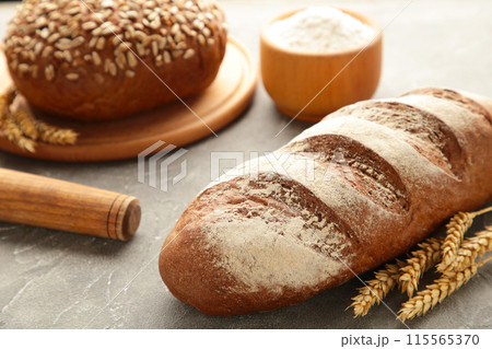 Delicious freshly baked brown bread on grey wooden background 115565370