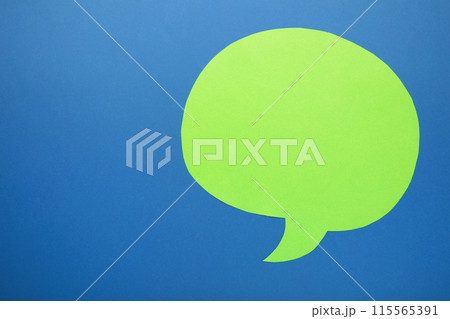 Green paper speech bubble on blue background 115565391