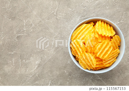 Potato chips in blue bowl on grey concrete background with copy space Potato chips in blue bowl on grey concrete background with copy space 115567153