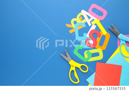 Scissors and colored paper for children's art on blue background 115567335