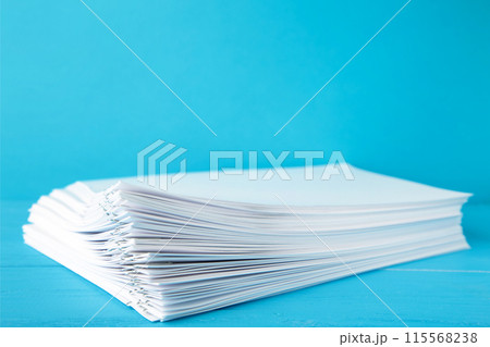 Colorful paper clip with pile of overload white paperwork on blue 115568238