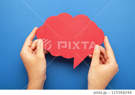Hands holding an red empty speech bubble on blue background 115568248