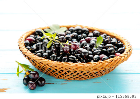 Basket with black currant on blue wooden background with copy space 115568395