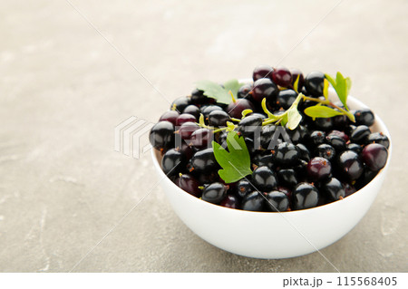 Black currant in a white bowl on grey concrete background 115568405