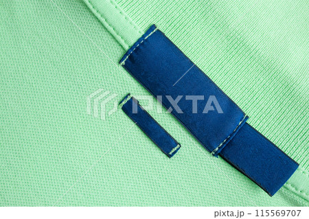 Blank blue laundry care clothes label on green shirt fabric texture background Blank blue laundry care clothes label on green shirt fabric texture background 115569707