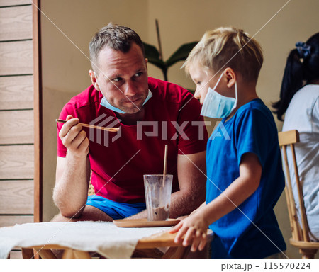 Father and son eat chocolate dessert with spoons in Cafe. Spending time together. Sweet tooth. Happy childhood Father and son eat chocolate dessert with spoons in Cafe. Spending time together. Sweet tooth. Happy childhood 115570224
