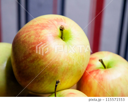 Vibrant Apple Detail. A colorful apple in the foreground with a textured skin, surrounded by blurred apples, representing natural health. Vibrant Apple Detail. A colorful apple in the foreground with a textured skin, surrounded by blurred apples, representing natural health. 115571553