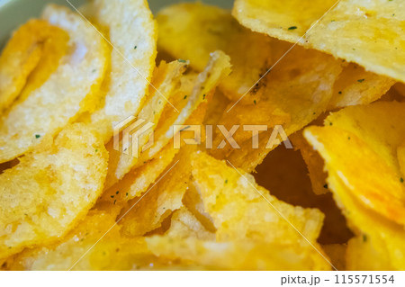 Crispy Snack Close-Up. Close-up of crispy potato chips with visible seasoning. 115571554