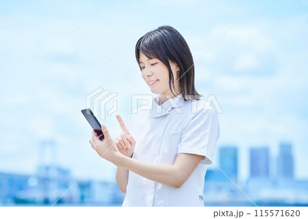 白衣を着てスマートフォンを操作する若い女性 白衣を着てスマートフォンを操作する若い女性 115571620