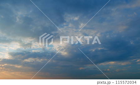 Beautiful sunset with cirrus clouds. Sun shines at level of horizon and warm tones colors. Timelapse. 115572034