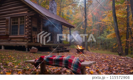 A cozy log cabin nestled in the woods with a fire pit burning in front of the porch A cozy log cabin nestled in the woods with a fire pit burning in front of the porch 115572908
