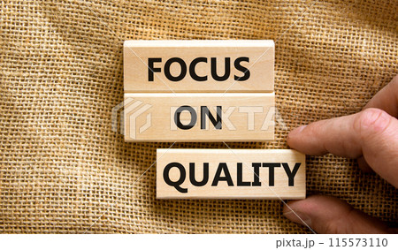Focus on quality symbol. Concept words Focus on quality on blocks on beautiful canvas table canvas background. Businessman hand. Business, focus on quality concept. Copy space. 115573110