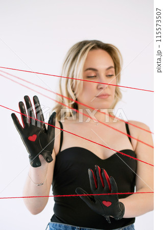 An adult woman in black gloves with a heart with red threads. An adult woman in black gloves with a heart with red threads. 115573507