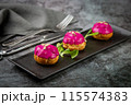 dessert of baked buns with raspberry topping and seed decorations, side view 115574383
