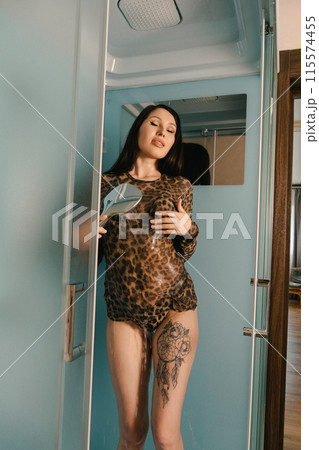 Woman in Leopard Print Shirt Looking in Hand Mirror in Bathroom Woman in Leopard Print Shirt Looking in Hand Mirror in Bathroom 115574455