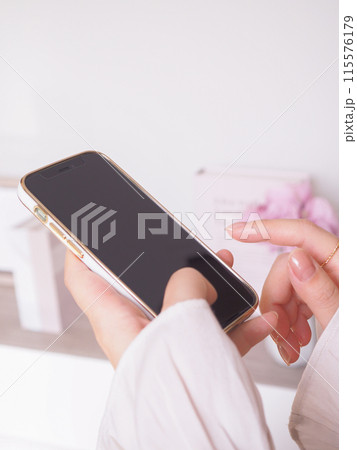 スマートフォンを操作する女性の手元と女性らしいインテリアの部屋 スマートフォンを操作する女性の手元と女性らしいインテリアの部屋 115576179