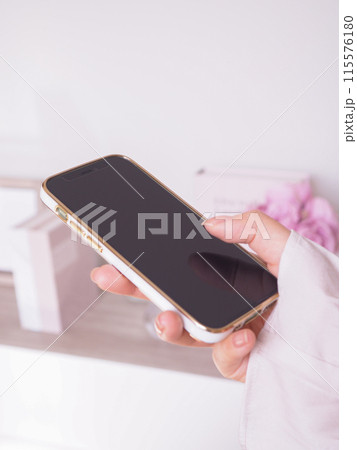 スマートフォンを操作する女性の手元と女性らしいインテリアの部屋 スマートフォンを操作する女性の手元と女性らしいインテリアの部屋 115576180