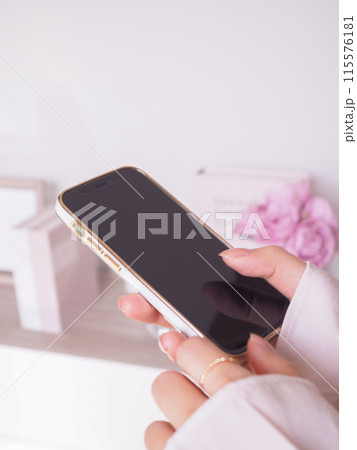 スマートフォンを操作する女性の手元と女性らしいインテリアの部屋 スマートフォンを操作する女性の手元と女性らしいインテリアの部屋 115576181