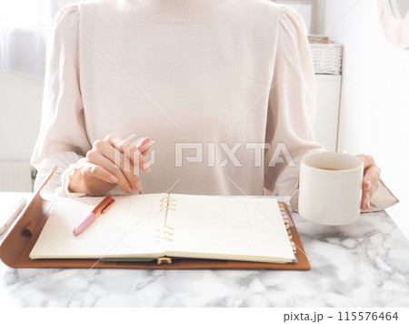 部屋でくつろぎながら手帳を開く女性	 115576464