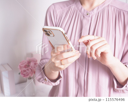 スマートフォンを操作する女性と女性らしいインテリア	 115576496