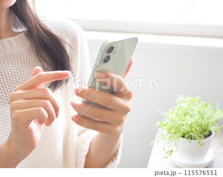 スマートフォンを操作する女性と清潔感のある部屋 115576551