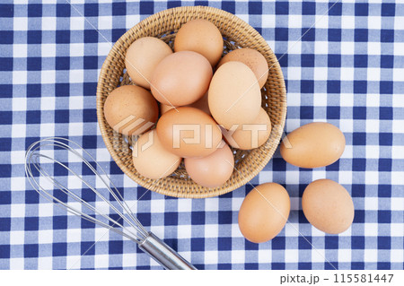 The Fresh raw eggs in the basket on blue tablecloth The Fresh raw eggs in the basket on blue tablecloth 115581447