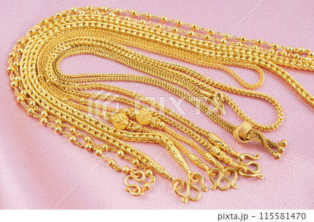 Many gold necklaces on pink velvet cloth. 115581470