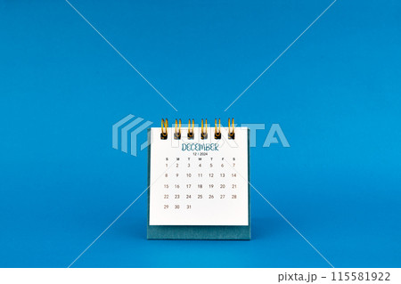 December 2024 mini desk calendar on blue background. 115581922