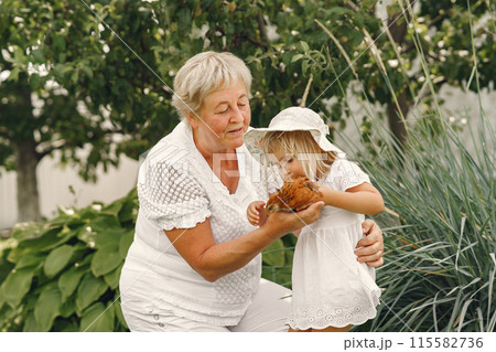 Family in a back yeard. Granddaughter with grandmother. People with little chicken. Family in a back yeard. Granddaughter with grandmother. People with little chicken. 115582736