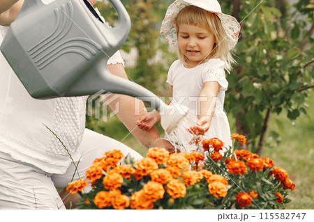 Small girl with senior grandmother gardening in the backyard garden. Child in a white hat. 115582747