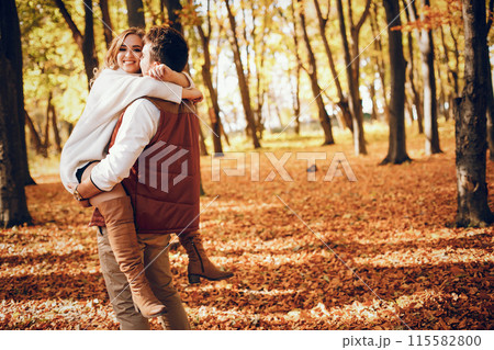 Couple have fun in a autumn park. Cute blode in a white sweater. 115582800