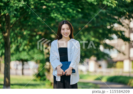 手帳を持って歩く若い女性 115584209