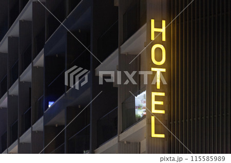 Illuminated yellow hotel sign by night 115585989