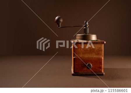 Vintage coffee grinder on brown background 115586601