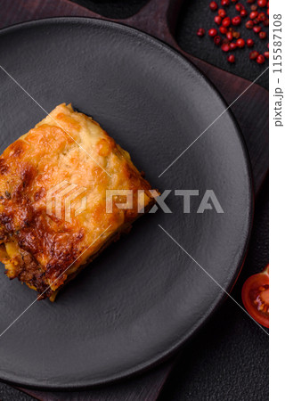 Delicious baked lasagna pasta with meat, sauce, salt, spices and herbs on a dark concrete background 115587108