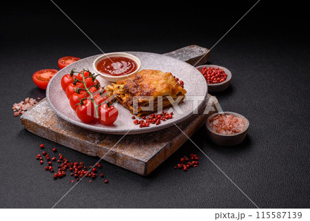 Delicious baked lasagna pasta with meat, sauce, salt, spices and herbs on a dark concrete background 115587139