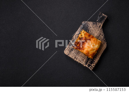 Delicious baked lasagna pasta with meat, sauce, salt, spices and herbs on a dark concrete background 115587153