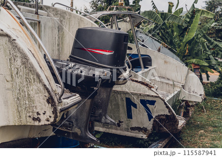 Old and rusty motor boats on a landfill surrounded by tropical forest 115587941