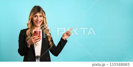 Excited transgender businesswoman holding smartphone while gesturing towards blank space Excited transgender businesswoman holding smartphone while gesturing towards blank space 115588065
