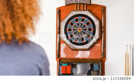 Anonymous man with dartboard in background at home 115588089