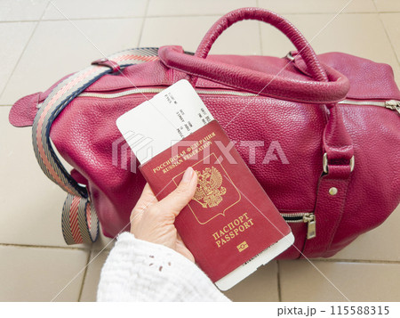 Russian red passport and boarding pass in a woman hand Russian red passport and boarding pass in a woman hand 115588315