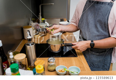 Chef at the kitchen preparing green curry with herbs and rice Chef at the kitchen preparing green curry with herbs and rice 115589613