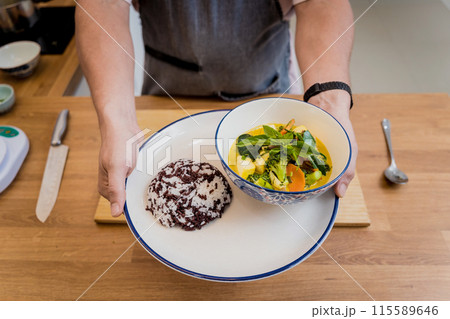 Chef at the kitchen preparing green curry with herbs and rice 115589646
