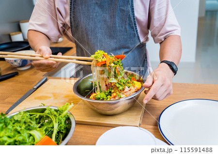 Chef at the kitchen preparing spicy glass noodle salad Chef at the kitchen preparing spicy glass noodle salad 115591488