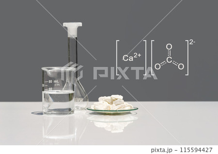 Calcium carbonate chip in chemical watch glass with molecular structure on white laboratory table. Side view Calcium carbonate chip in chemical watch glass with molecular structure on white laboratory table. Side view 115594427