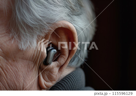 Ear of an elderly person with hearing aid 115596129