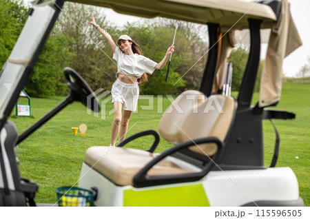 Active woman posing with golf gear by the vehicle outside 115596505