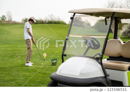 Young guy exercising in playing golf and looking concentrated 115596531