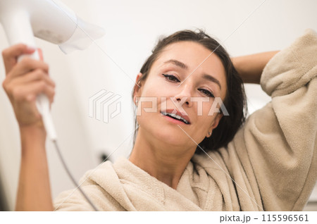 Pretty happy woman drying her hair and smiling 115596561
