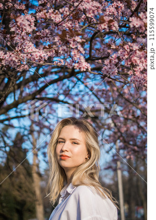 Woman with cherry flowers surrounded by blossoming trees copy space. Beauty and seasonal change and spring bloom season concept. Woman with cherry flowers surrounded by blossoming trees copy space. Beauty and seasonal change and spring bloom season concept. 115599074